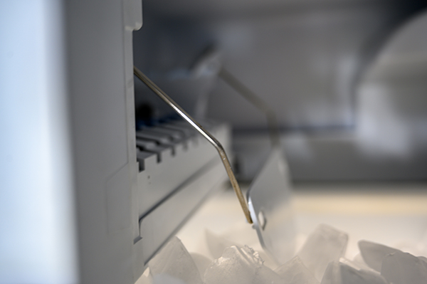 Inside a freezer automatic ice maker with pile of cubes Overfilled or Damaged Ice Maker